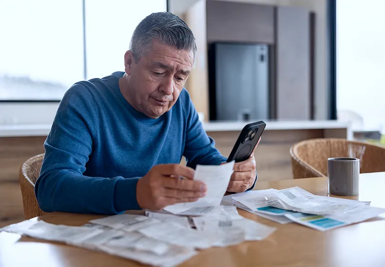 Older homeowner reviewing bills at a table.